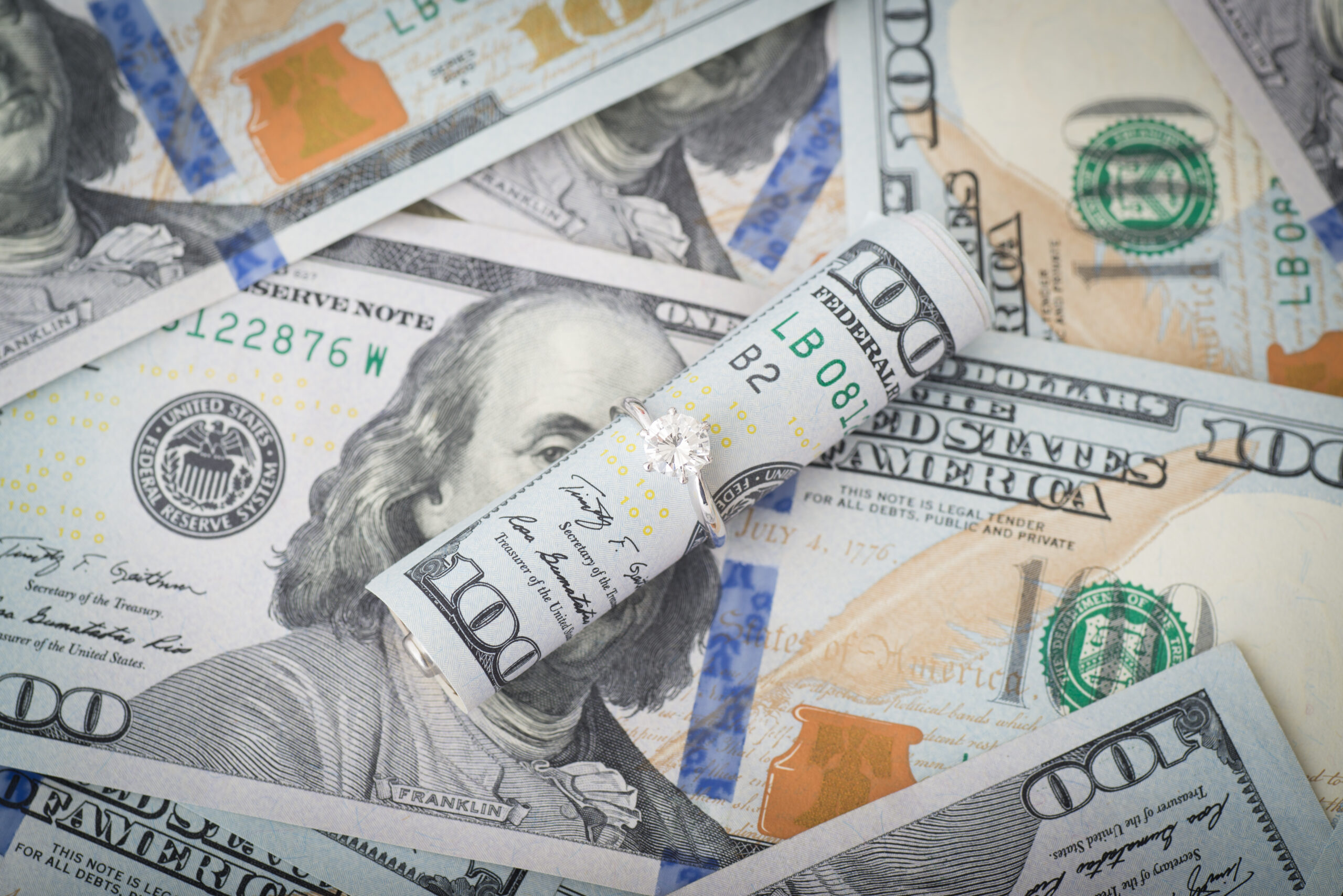 money and diamond ring in a pile; How Much Does a Divorce Cost? concept image