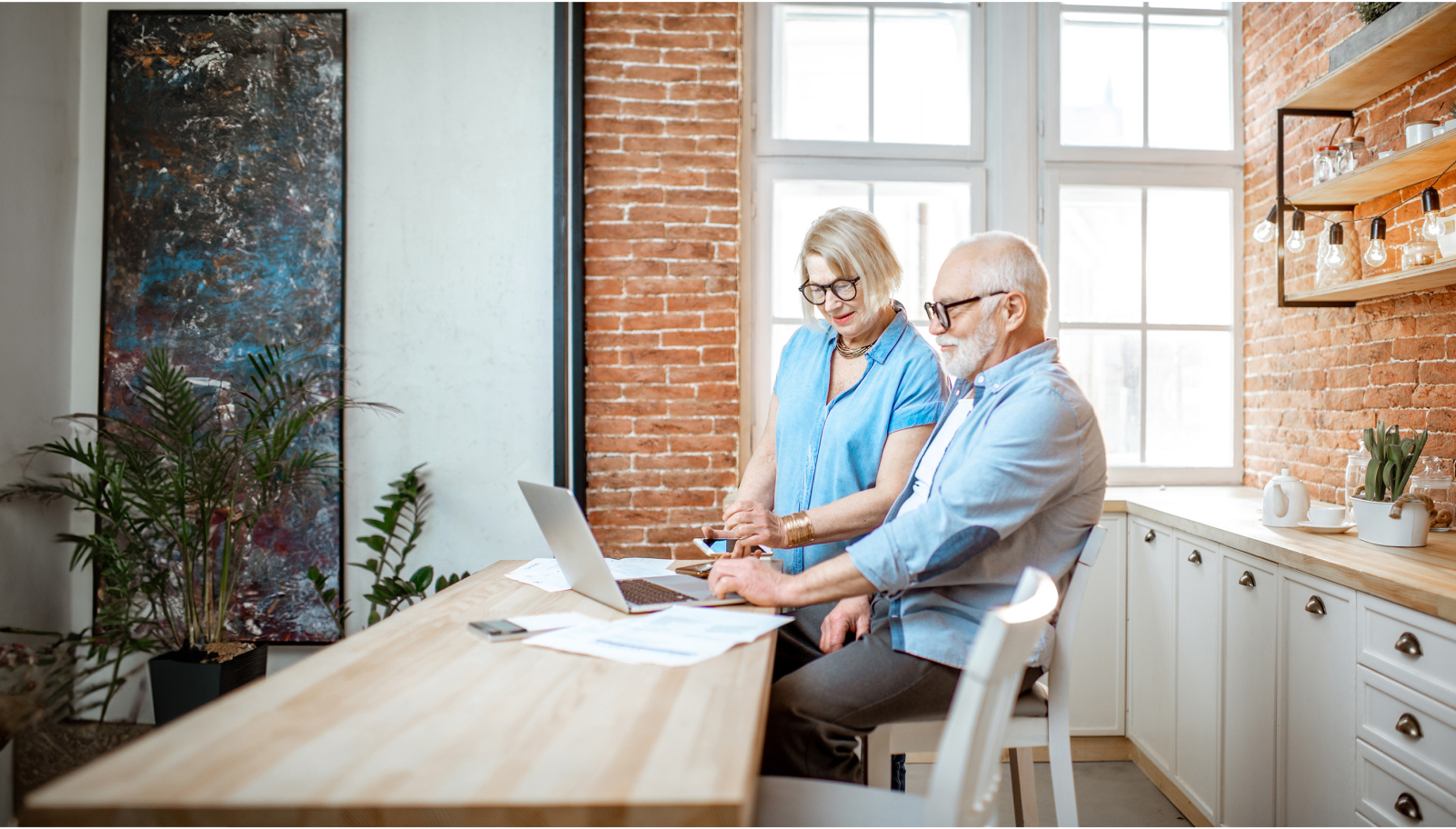 senior couple sitting at a table with a laptop at home