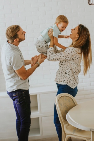 Mom and dad holding their young child and smiling.