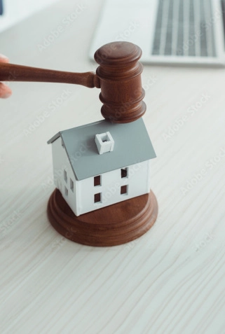 Gavel over a house model on a table