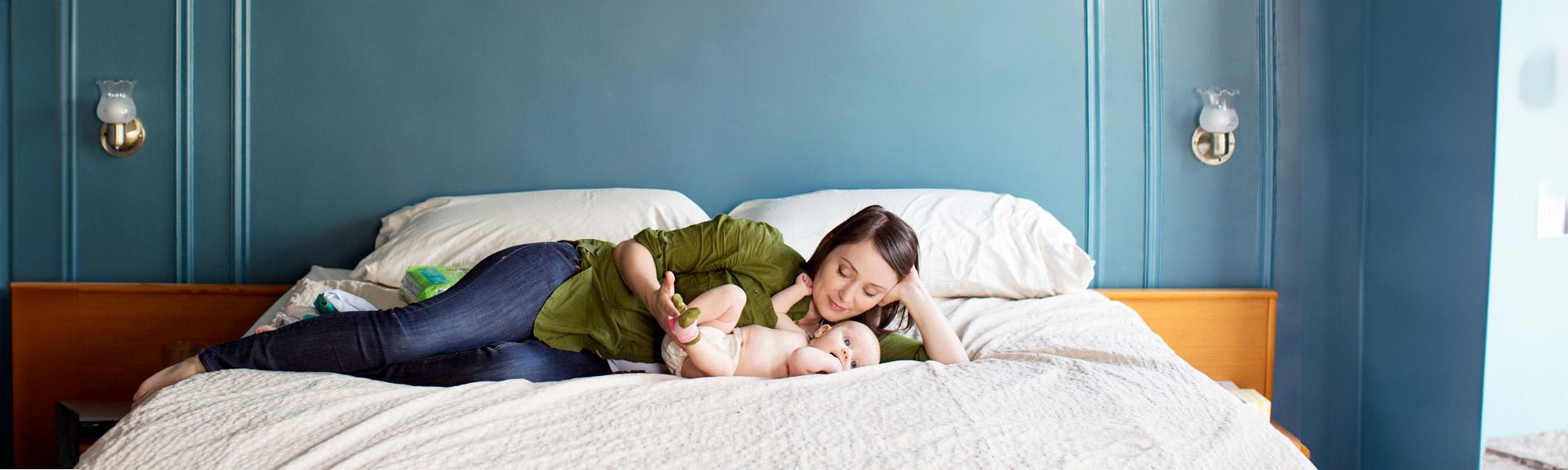 mother playing with her baby on bed at home
