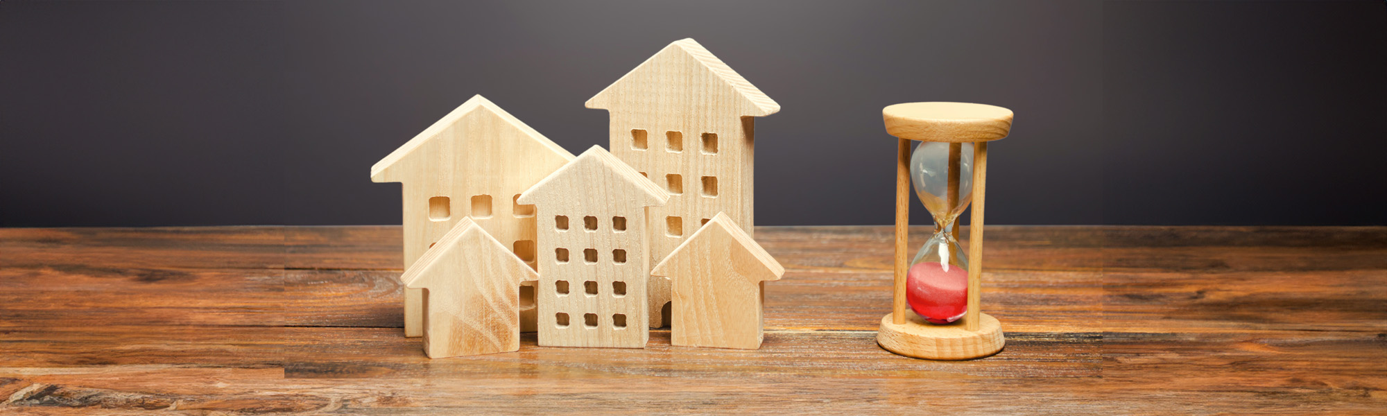 wooden figures of houses and sand hourglass