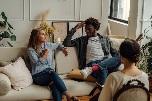 couple talking on couch in front of other person