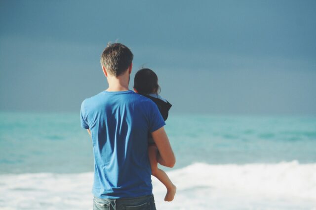 Man holding child by ocean