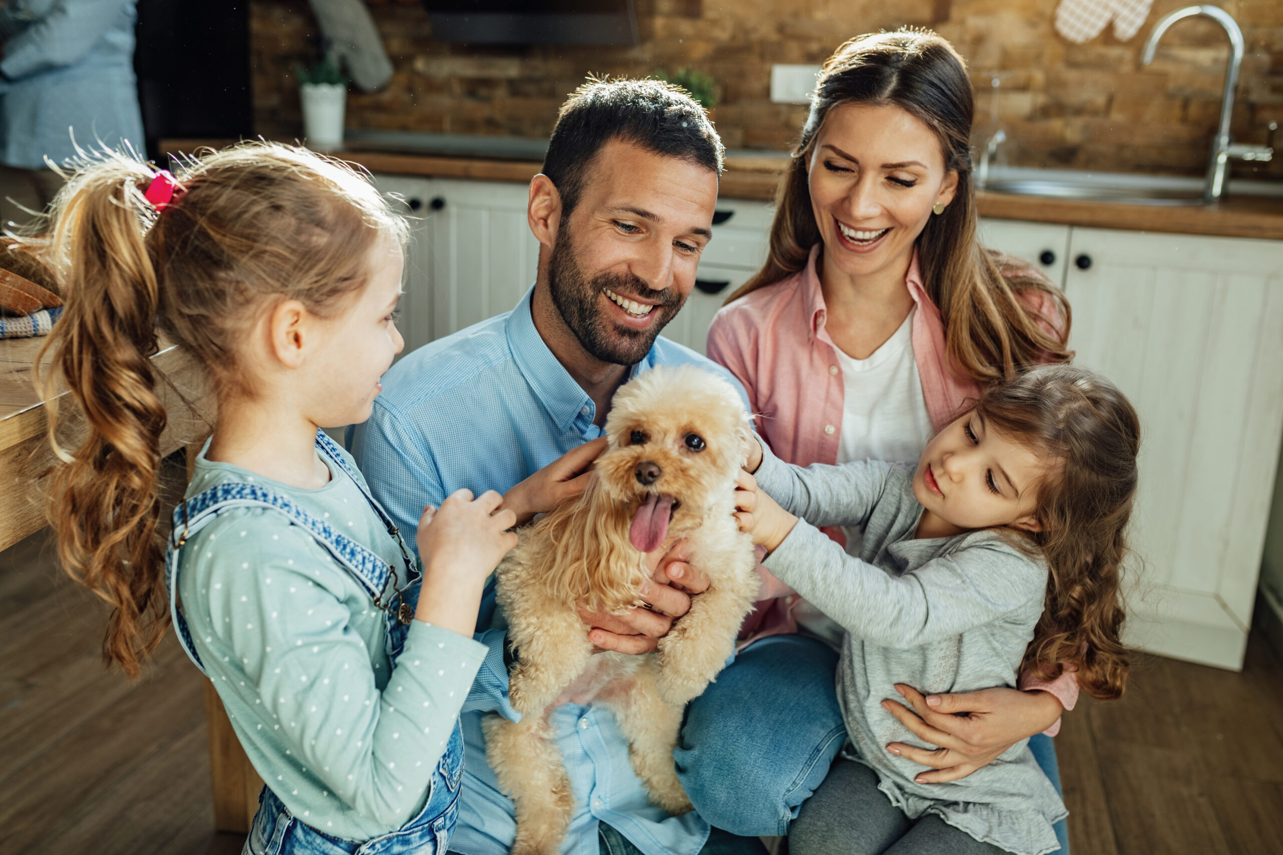 Young happy family having fun with their dog at home.